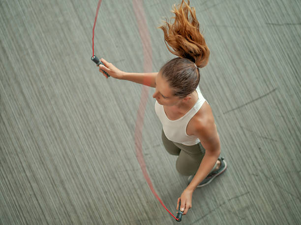 Young sportive woman doing exercises with jumping rope in the gym
