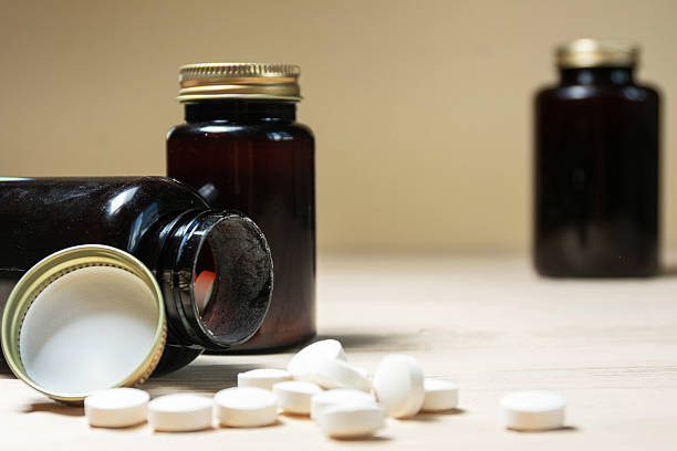 istock Two Brown Bottles with Scattered White Pills on Wooden Table 2229953753