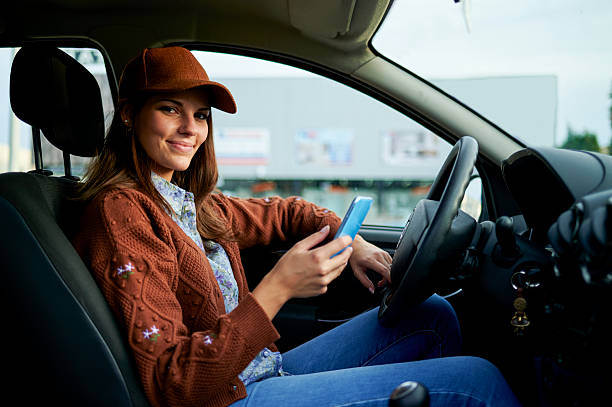 istock <Woman using mobile phone while driving car, looking at camera 2229958289