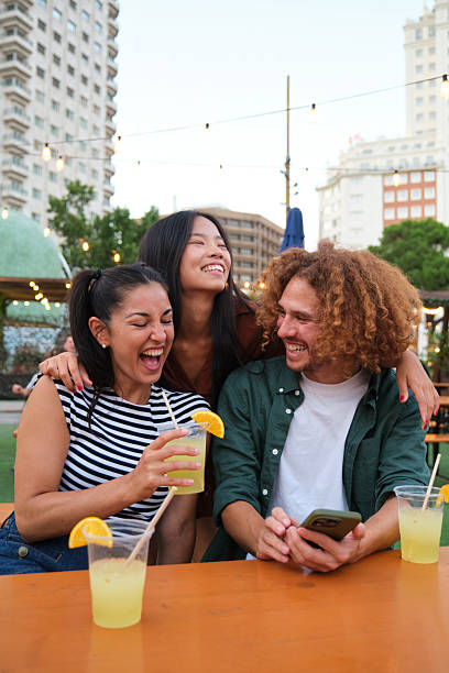 Young friends laughing and drinking lemonade at a summer party in Madrid