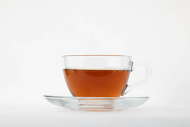 istock a clear glass teacup filled with dark brown liquid, likely black tea, resting on a matching clear glass saucer 2229961203