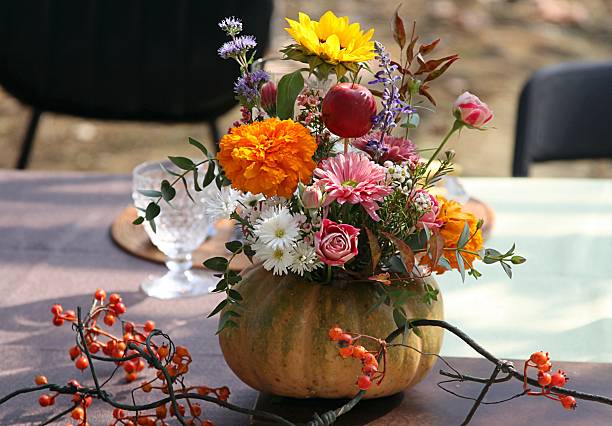 A carefully arranged centerpiece of ripe persimmons and delicate wildflowers evokes the gentle spirit of the fall season in a natural and handmade aesthetic.