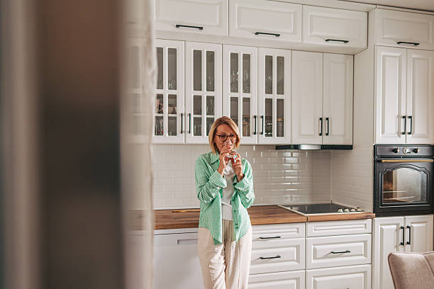 istock Woman drinking water in a modern kitchen 2229964092