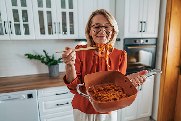 istock Senior woman enjoying freshly cooked pasta in modern kitchen 2229970370