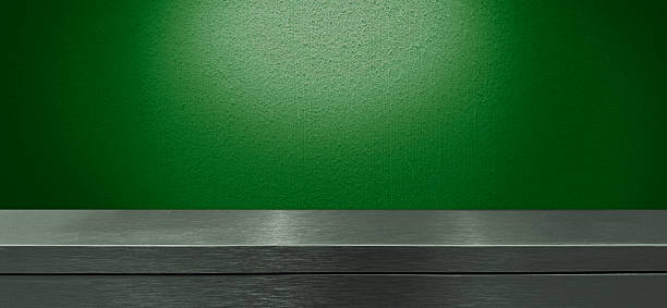istock brushed stainless steel counter or table at foreground with green wall at background, showing a clean and reflective surface use as background. 2229972870
