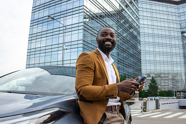 istock Confident businessman smiling while standing by his car in an urban setting 2229973047