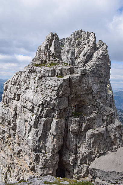 Man rock climber climbing a vertical rock face in beautiful mountain landscape at sunset