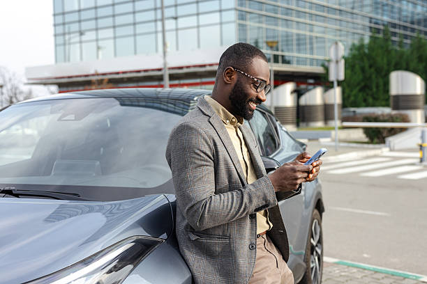 istock Businessman leaning on a car while using a smartphone outdoors 2229973660