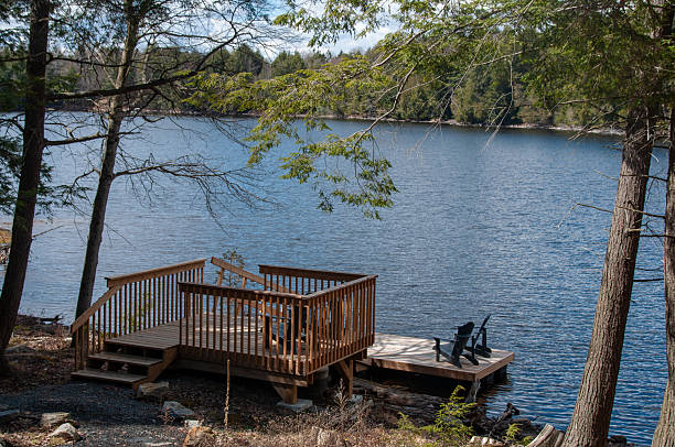 istock A wooden dock with chairs on a beautiful blue lake surrounded by forest 2229979312