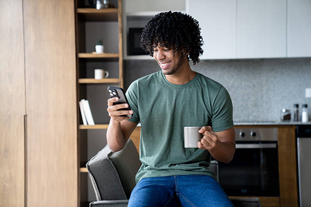 istock Happy man at home looking at social media on his phone while drinking coffee 2229982680