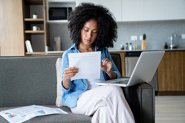 istock Young woman working at home using her laptop and reading a document 2229982681