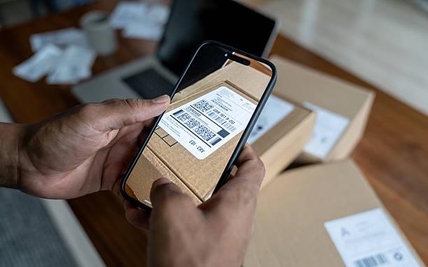 Close-up on a man scanning the label of a package using his cell phone while running an e-commerce business