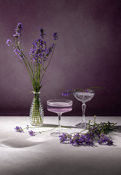 Lavender flowers in vase and coupe glasses on white table