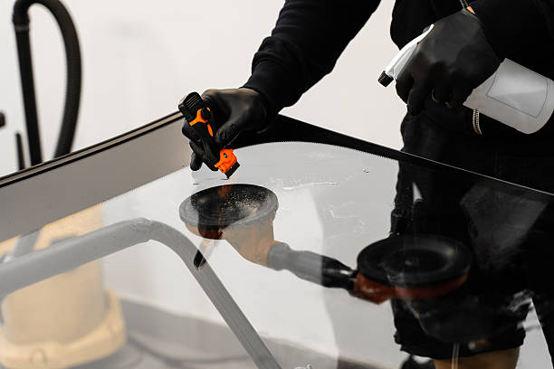 istock Technician scrapes and cleans new windshield after replacement to ensure perfect adhesion. Technician uses scraper to clean the surface of a new windshield post-replacement. 2229983527