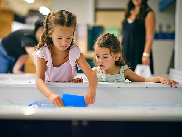 Children playing with an interactive water table exhibit in a children’s museum.