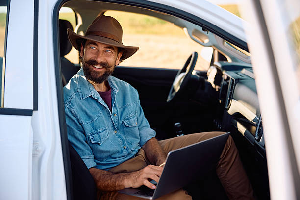 istock Happy farmer using laptop while sitting inside of his pick-up truck. 2229986072