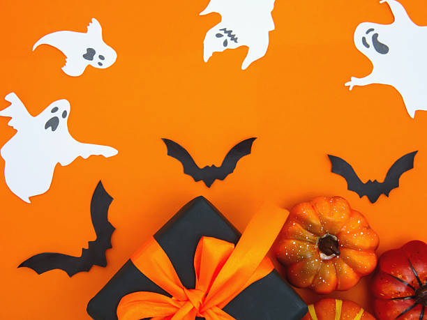 istock A gift box with orange bows, small pumpkins and decorations on an orange background create a festive mood for Halloween 2229986095