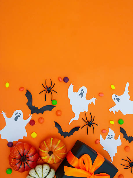 istock A gift box with orange bows, small pumpkins and decorations on an orange background create a festive mood for Halloween 2229986254