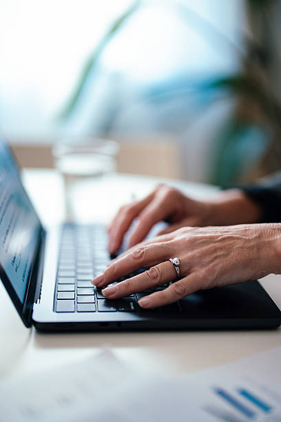 Close-Up of Hands Typing on a Laptop in a Modern Office Setting