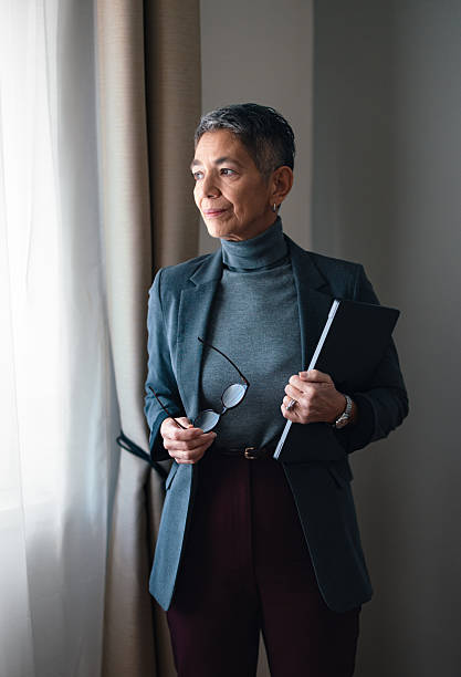 Confident Businesswoman Holding Documents Standing by a Window in Natural Light