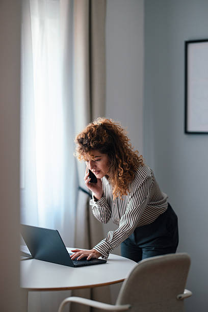 istock Businesswoman Using Laptop and Phone in Bright Office Workspace 2229986950