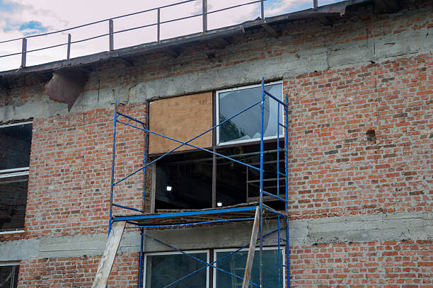 istock Workers install windows on a brick structure as scaffolding supports the building, showcasing ongoing renovations in the area 2229988099
