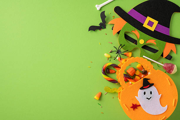 istock Festive Halloween items including masks, candy pieces, and decorations arranged on a vivid surface 2229990271