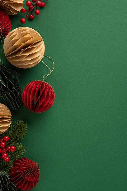 istock Colorful vertical decorative Christmas ornaments and evergreen foliage on a green backdrop for seasonal decor 2229990318