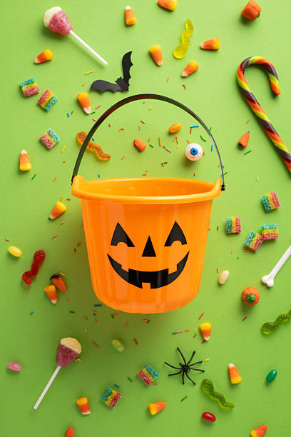 istock Festive vertical Halloween scene featuring a pumpkin bucket surrounded by assorted colorful candies 2229990323