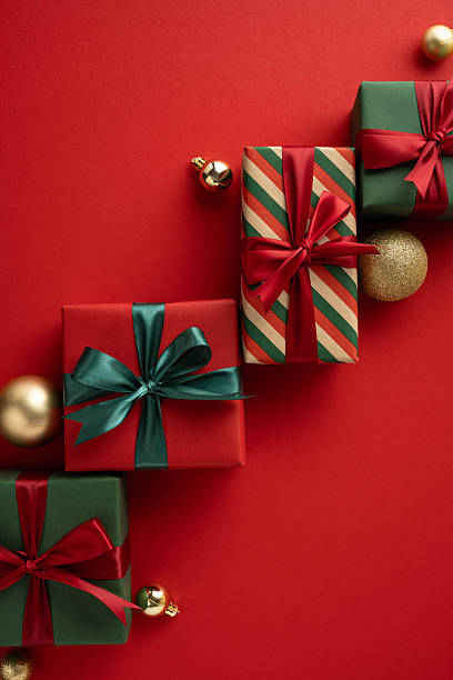 istock Gift boxes decorated with bows and holiday ornaments on a vertical red festive surface, symbolizing Christmas joy and celebration 2229990335