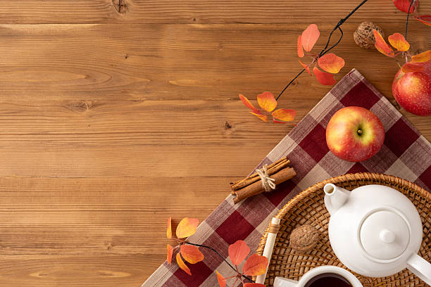istock Autumn scene featuring apples, cinnamon sticks, tea pot, and leaves on a wooden surface 2229990350