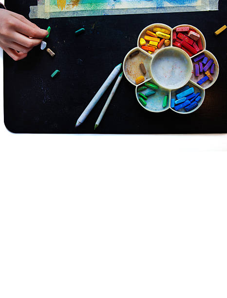 istock Top view of a hand arranging colorful pastel chalks in rainbow palette with blending tools on a black table 2229990666