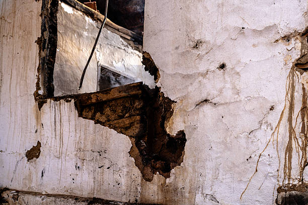 Detail of a weathered and damaged wall, showcasing erosion and structural deterioration. The image highlights textures and flaws in the wall's surface, emphasizing years of wear and tear. This serves as a representation of time, imperfection, and the effects of natural forces.