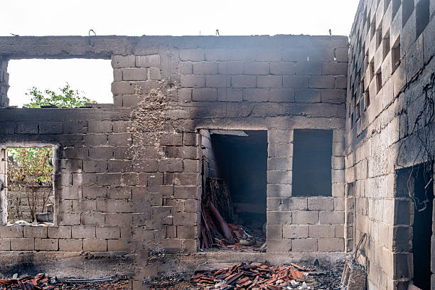 Charred structure remaining after a severe fire incident with visible damage A damaged building remains after a fire, with burnt walls and debris scattered around. The general destruction evokes a sense of loss and hardship, highlighting the impact of fire incidents on constructed environments. A poignant reminder of the resilience required to rebuild after such devastation. Fire Damage Repair.