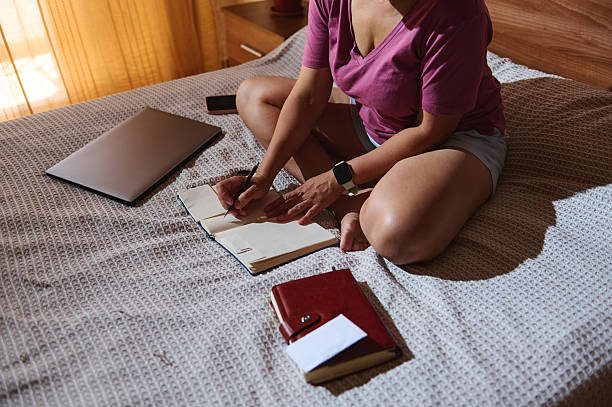istock Woman Writing Notes on Bed in Relaxed Home Environment 2229994110