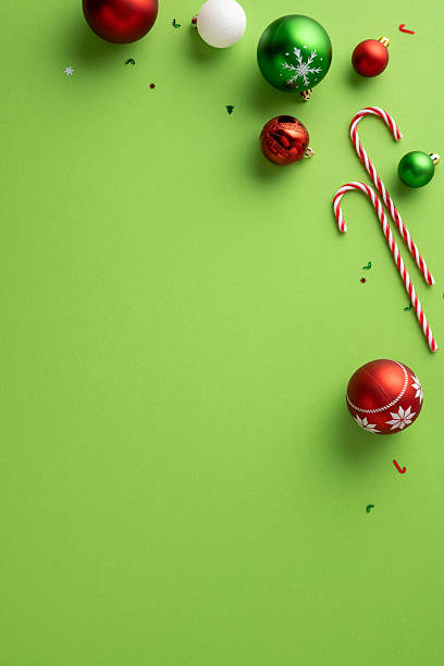 istock Colorful vertical Christmas ball ornaments and candy cane decorations placed on a green background 2229995144