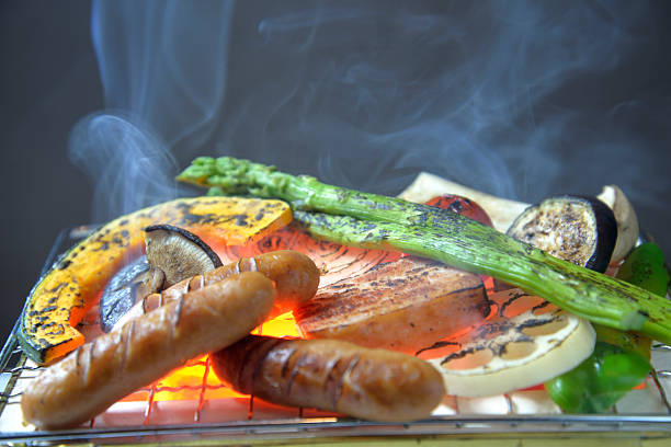 Grilling meat and vegetables on a smoky charcoal grill
