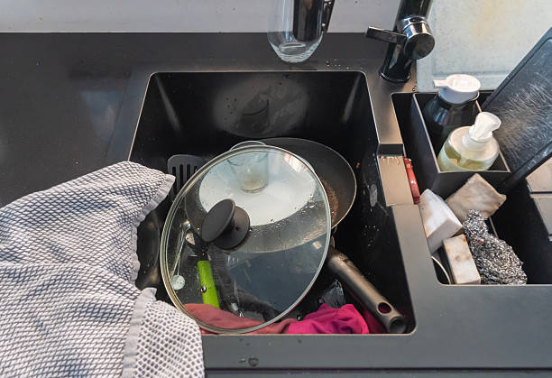 istock Cluttered kitchen sink overflowing with unwashed dishes, pots, and cooking tools, representing domestic chaos and overwhelming daily responsibilities 2229999393
