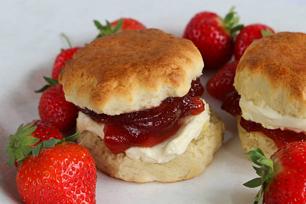 istock Full frame image of plain scones with strawberry jam and clotted cream on white plate with strawberries, traditional English afternoon tea topped with jam and cream in the Cornish and Devonshire ways, elevated view,  social debate concept 2230001105