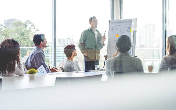 istock Business people watching a presentation on the whiteboard. A man is writing on the whiteboard with charts and graphs 2230003000