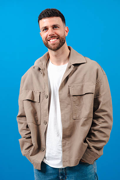 istock Smiling man in casual beige jacket standing against blue background 2230003123