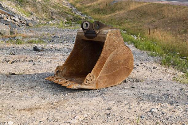 A whimsical excavation machinery bucket adorned with googly eyes playfully situated in a picturesque rural landscape