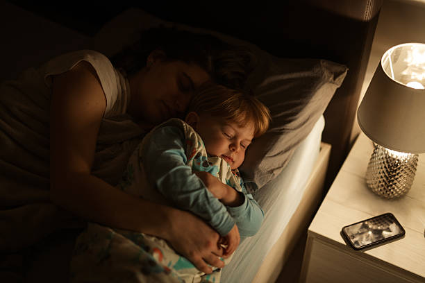 istock Mother and child cuddling and sleeping together at night. 2230015082