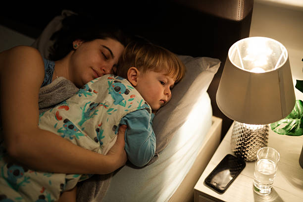 istock Mother and child cuddling and sleeping together at night. 2230015087