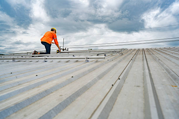 Technician in safety uniform and helmet kneeling on a rooftop, using a drill for precise installation work. A scene highlighting safety, professionalism, and technical expertise in construction.