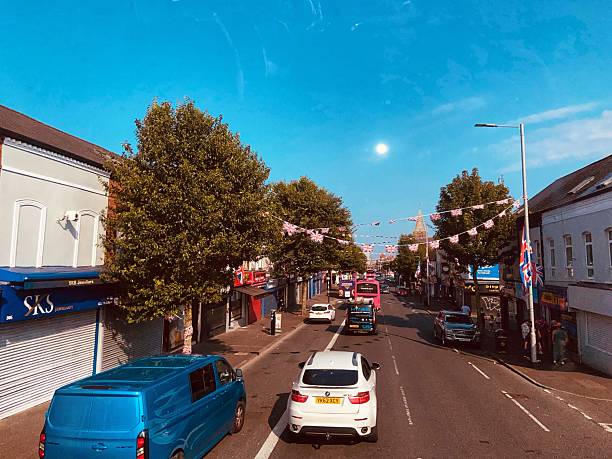 Belfast, United Kingdom - August 12, 2025. A sunny street lined with trees and adorned with Union Jack flags strung across.