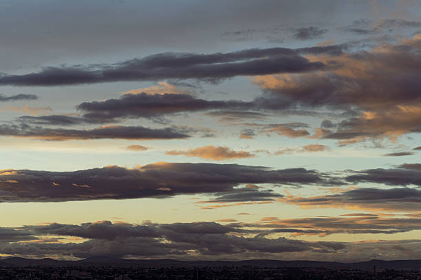 The sky is dark and cloudy with a few clouds in the distance. The sun is setting, casting a warm glow over the landscape