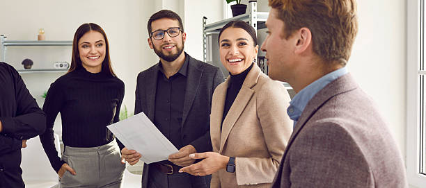 istock Positive colleagues standing and discussing new project in office 2230025386