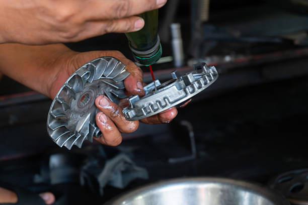Detailed close-up of a mechanic’s hand performing maintenance on a scooter motorcycle’s CVT (Continuously Variable Transmission) system in a professional workshop. Ideal for illustrating concepts.