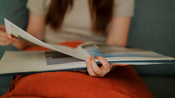 istock Woman looking at pictures in a book while reading peacefully 2230039339